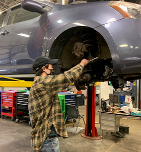 Student working on lifted car