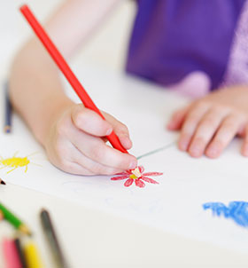 Child drawing flowers at a table
